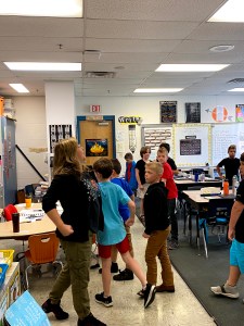 A Teaching Artist and young students in class walking as if they are carrying heavy armor on their bodies.
