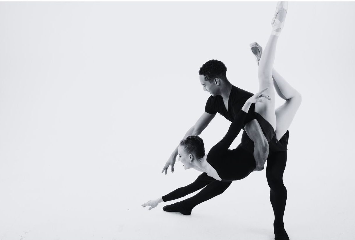 A ballerina being dipped towards the ground by another dancer.